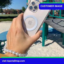 Load image into Gallery viewer, Image of customer of holding Aporia MagSafe Clear Case - Pearl Wristlet Strap for iPhone 15/14/13/12 at playground
