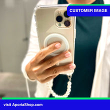 Load image into Gallery viewer, Image of customer holding Aporia MagSafe Clear Case - Pearl Wristlet Strap for iPhone 15/14/13/12 inside fitting room
